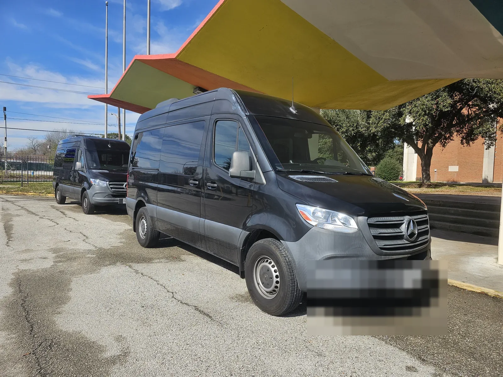 Two Mercedes Sprinter vans parked at the Houston to Galveston Shuttle Co. yard