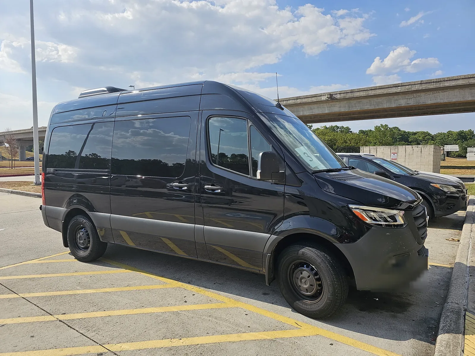 Mercedes Sprinter shuttle van parked at a Houston airport pick-up area